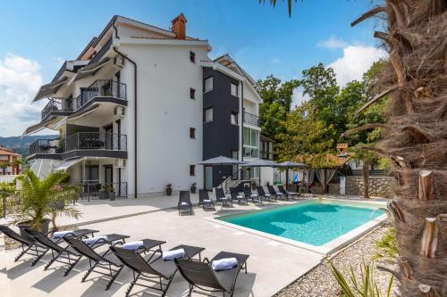 una foto di una villa con piscina e sedie di Villa Adriatic, Apartment Chiara with sea view and heated swimming pool, free private parking, a Ičići