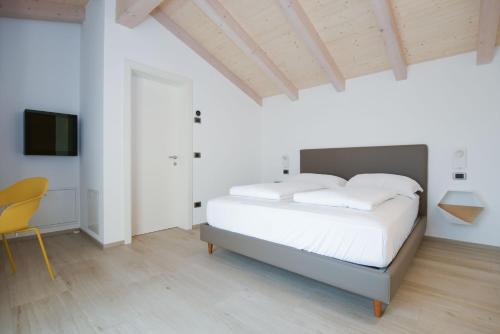 a white bedroom with a bed and a chair at Agritur Casteller in Trento
