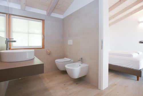 a bathroom with a sink and a toilet and a bed at Agritur Casteller in Trento