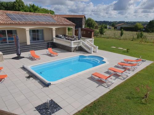 a swimming pool with chairs and a house at villa 15 personnes avec piscine et terrain de pétanque in Puysserampion