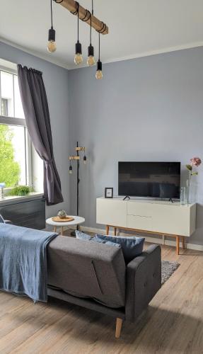 a living room with a couch and a tv at Goethes liebste Betten - stilvolle Ferienwohnungen im historischen Fachwerkhaus in Wernigerode - Parkplatz, Smart-TV, W-Lan in Wernigerode