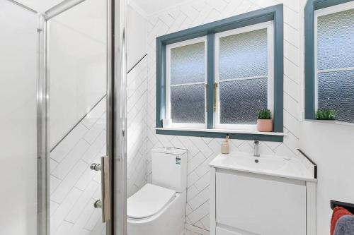 a bathroom with a toilet and a sink and a window at HOH - Hazel's Homestead in Matamata