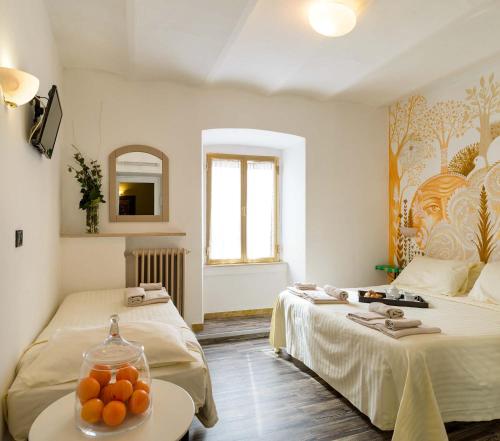 a room with two beds and a table with oranges on it at Hotel San Francesco e il lupo in Gubbio