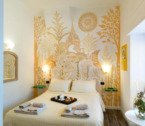 a bedroom with a white bed with a gold patterned wall at Hotel San Francesco e il lupo in Gubbio