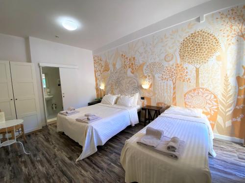 a hotel room with two beds and a wall mural at Hotel San Francesco e il lupo in Gubbio