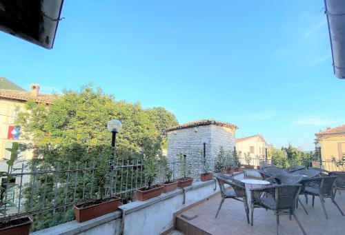 a patio with tables and chairs on a balcony at Hotel San Francesco e il lupo in Gubbio