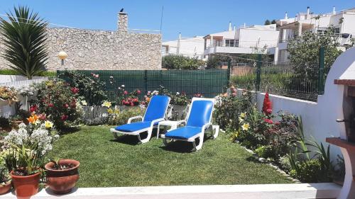 two blue chairs sitting in a yard with flowers at Villa Ciriaco Sea Star in Ericeira