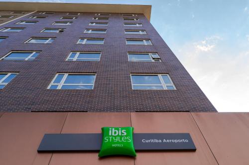 a tall building with aubs plus sign in front of it at ibis Styles Curitiba Aeroporto in São José dos Pinhais