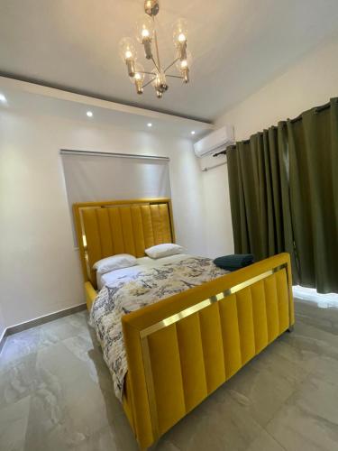 a yellow bed in a room with a chandelier at Villa con piscina Verdana SFM in San Francisco de Macorís