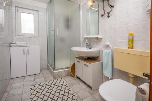 uma casa de banho com um lavatório, um WC e um espelho. em Apartment Kucinic em Rogoznica