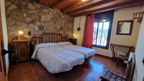a bedroom with a bed and a stone wall at El Jardí de la Vileta - Cornudella de Montsant in Cornudella