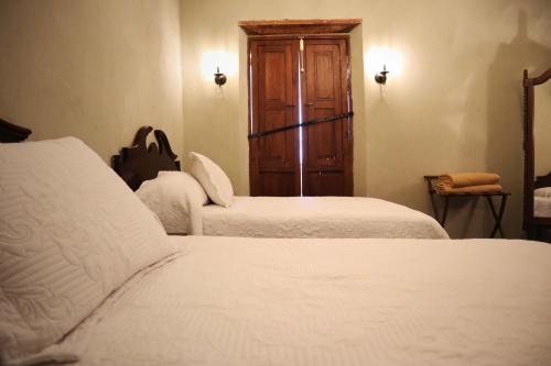 La Casa del General Hotel Boutique في هيدالجو ديل بارال: غرفة نوم بسريرين وخزانة خشبية