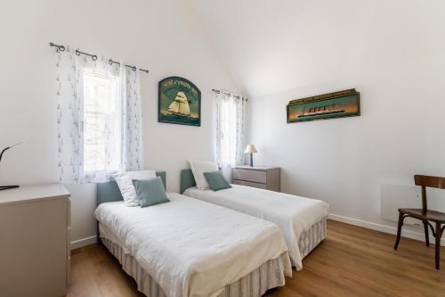 Duas camas num quarto com paredes brancas em Jolie Brise em Pléneuf-Val-André
