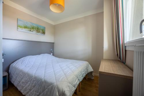 une chambre avec un lit blanc et une fenêtre dans l'établissement Le Cormoran, à Courseulles-sur-Mer