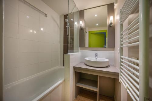 une salle de bain avec un lavabo, une baignoire et un miroir dans l'établissement Le Cormoran, à Courseulles-sur-Mer