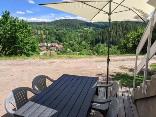 a blue picnic table with an umbrella on a deck at Appartement au centre du tholy pour 5 personnes maximum in Le Tholy