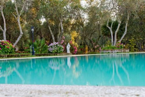 a swimming pool in a park with flowers and trees at Agriturismo Il Riccio in Forni di Gavorrano