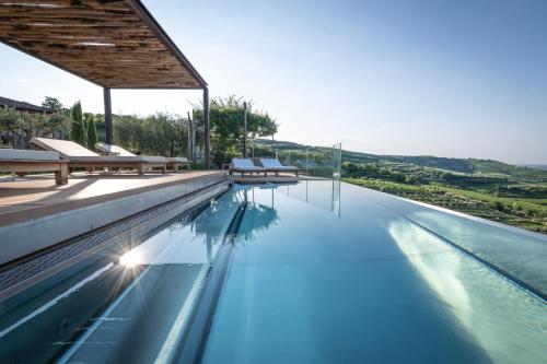 a swimming pool with benches on the edge of the water at Relais di Campagna I Tamasotti in Mezzane di Sotto