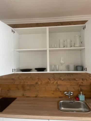 una cocina con estanterías blancas y fregadero en Apartment Dubnica-Prejta 2 en Dubnica nad Váhom