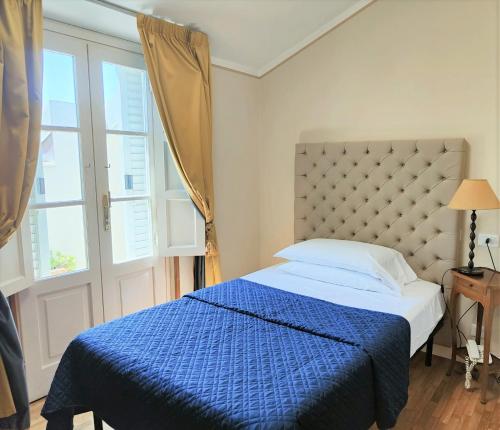a bedroom with a bed with a blue comforter and a window at Hotel Europa in Lido di Camaiore
