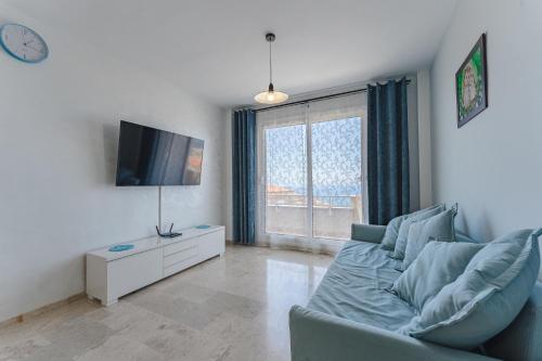 een woonkamer met een blauwe bank en een tv bij Santiago Astalavista sea view 4 in Puerto de Santiago