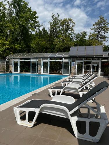 a row of lounge chairs next to a swimming pool at Nyerges Hotel Termál Superior in Monor