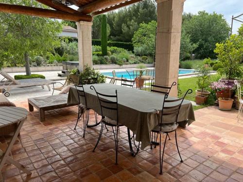 - une table et des chaises sur une terrasse avec piscine dans l'établissement Mas des IRIS, à Saint-Rémy-de-Provence