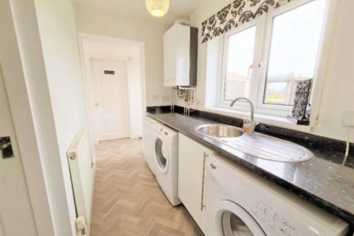 a kitchen with a sink and a washing machine at Bike Park Lodge #2 in Merthyr Tydfil