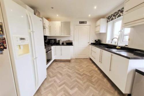 a kitchen with white cabinets and a wooden floor at Bike Park Lodge #2 in Merthyr Tydfil