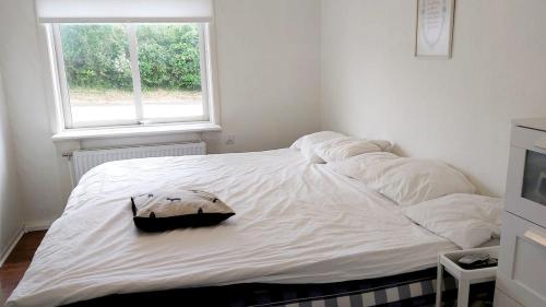 ein weißes Bett in einem Zimmer mit Fenster in der Unterkunft Cottage Halle-Hunneberg in Vargön