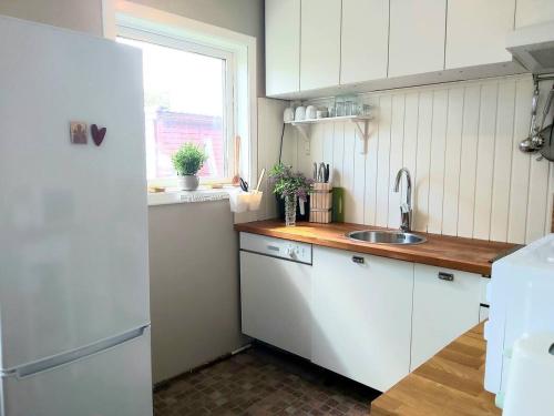 eine Küche mit einem weißen Kühlschrank und einer Spüle in der Unterkunft Cottage Halle-Hunneberg in Vargön