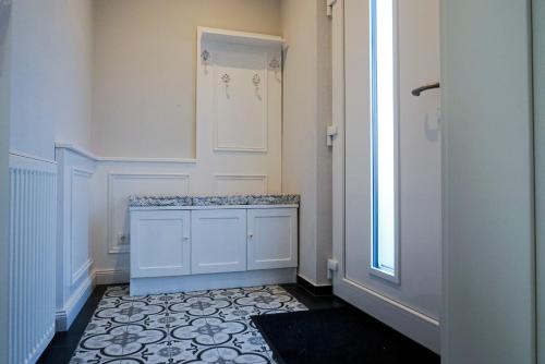 bagno con armadio bianco e pavimento piastrellato. di Zauberhaftes Stadthaus ad Altötting