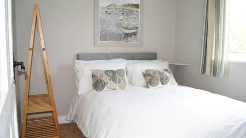 sypialnia z białym łóżkiem z poduszkami i drabiną w obiekcie Bubbles on the bay w mieście Waterford