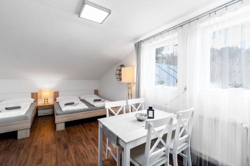 a room with two beds and a table and chairs at Pension Lesná in Jiřetín pod Jedlovou