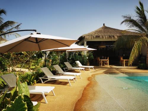 a group of chairs and umbrellas next to a pool at La Maison Vanille in Ngaparou