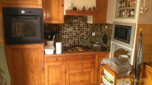a kitchen with wooden cabinets and a microwave and a tv at petit chez soi dans mon petit chez moi in Biganos