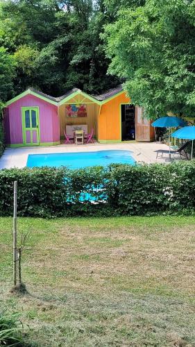 une maison dotée d'une piscine avec une table et des parasols dans l'établissement Les Bambous, à Sauveterre-la-Lémance