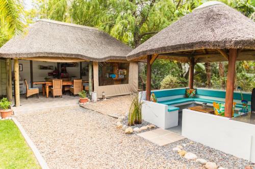 a villa with a pool and a thatch roof at Khashamongo B & B in Somerset West