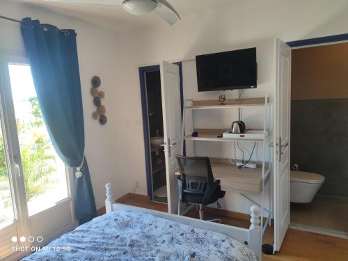 a bedroom with a bed and a desk and a television at L'annexe du font Blanque in Campsas