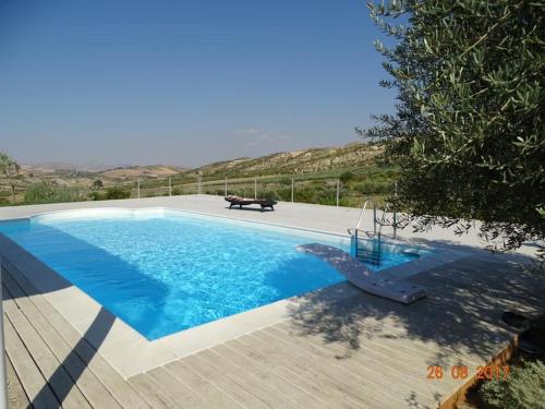 ein blauer Pool mit einer Bank daneben in der Unterkunft Villa Maria in Aragona