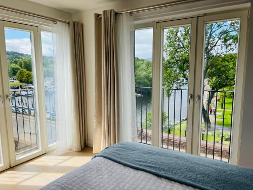 a bedroom with a bed and large glass windows at Riverside View Penthouse in Balloch, Loch Lomond in Balloch