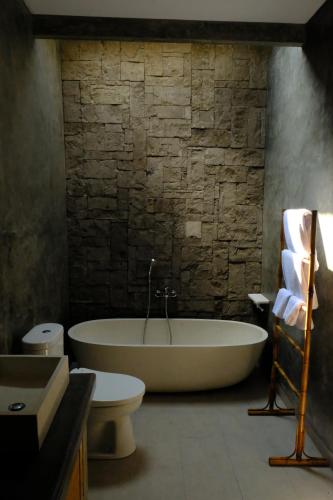 a bath tub and a toilet in a bathroom at Kidupa Villa in Ubud
