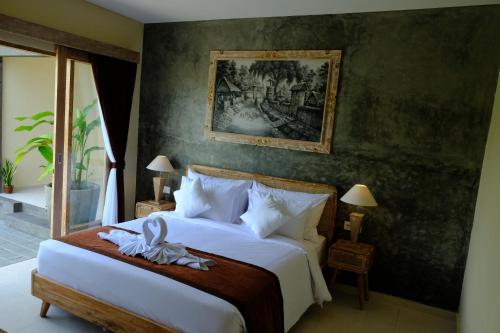 1 dormitorio con 1 cama y una pintura en la pared en Kidupa Villa en Ubud