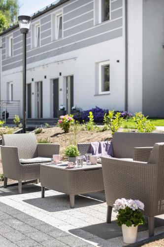 a patio with chairs and a table in front of a house at Apartamenty Wczasowa - z widokiem na góry, parkingiem, rowerownią in Kudowa-Zdrój