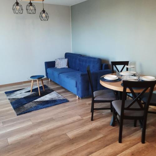 a living room with a blue couch and a table at Niebieski - Mala Apartamenty in Rumia