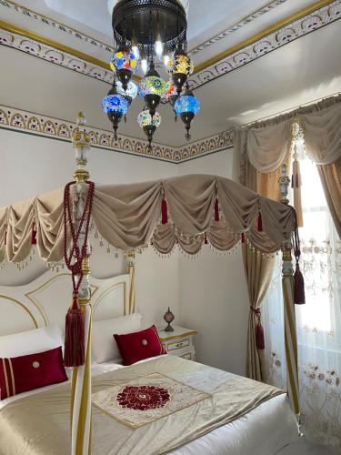 a bedroom with a canopy bed and a chandelier at Chambre Orientale Chérazade Maison de L'Église in Narbonne