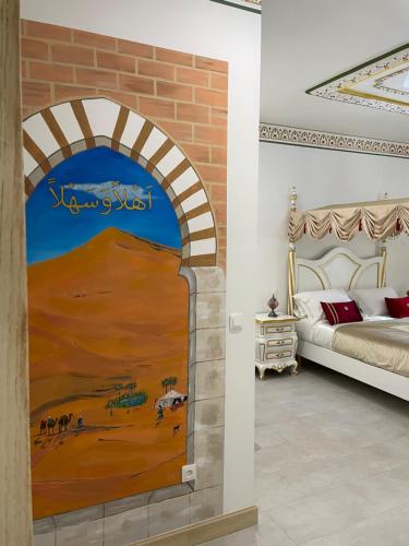 a bedroom with a painting of a desert at Chambre Orientale Chérazade Maison de L'Église in Narbonne