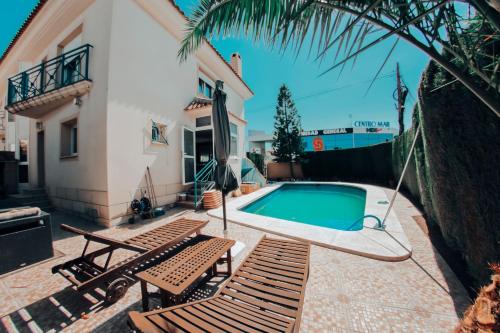 a swimming pool with two chairs and a house at Casa adosada con piscina privada in Alfaz del Pi
