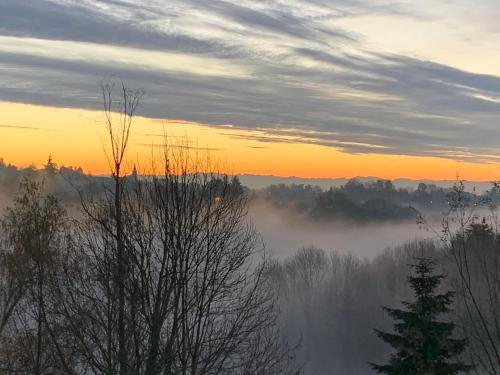 a view of a foggy valley with the sun setting at La Ferme du Puy d'Or in Limonest