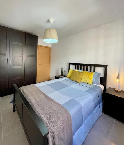 Un dormitorio con una gran cama azul con almohadas amarillas en UIM Mediterraneo Alicante Wifi en Puerto de Sagunto